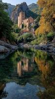 Ruins of an ancient castle reflect in serene waters surrounded by vibrant autumn foliage in a tranquil valley photo