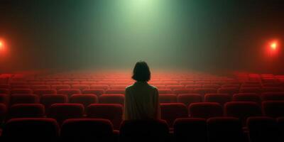 View of a person sitting alone in an empty theater with dim lighting and fog photo