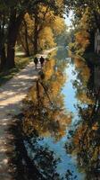 Serenity of autumn stroll by the tranquil waterway lined with golden trees in the late afternoon sun photo