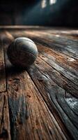 Basketball rests on aged wooden floor in dimly lit gym space showcasing its wear and history photo
