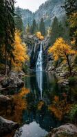 Majestic waterfall cascades into tranquil pool surrounded by autumn foliage in a serene mountain landscape photo
