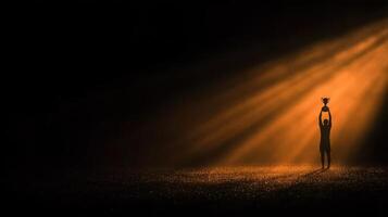 Dark silhouette holding a trophy under a dramatic spotlight in a festive atmosphere after a victorious event photo
