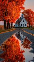 Vibrant autumn colors reflect in a calm puddle near a charming white house on a quiet rural road at sunset photo