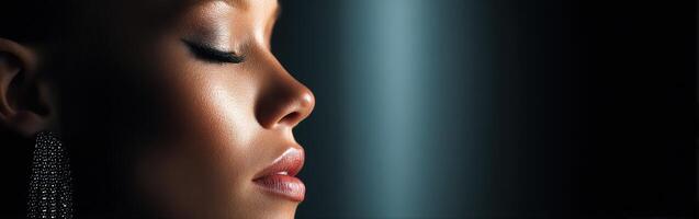 Profile view of a woman with elegant makeup and jewelry in dramatic lighting photo