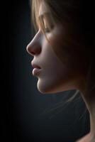 Portrait of a young woman illuminated by soft light against a dark background photo