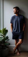 Casual man standing by window with potted plant in comfortable attire photo