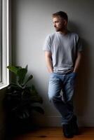 Young man standing by window in a cozy indoor setting during daylight photo