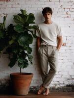 Young man posing casually by a potted plant in a rustic indoor setting photo