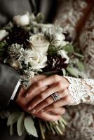 Couple's hands adorned with rings holding a beautiful bouquet at a wedding photo
