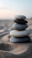 Stacked smooth stones create a tranquil display on sandy beach at sunset photo