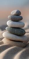 Calm balance of smooth stones stacked on sand at a beach during sunset photo