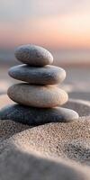 Four stones balanced on a sandy beach at sunset creating a peaceful scene photo