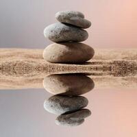 Balanced stones resting on smooth sand with reflection at sunset photo