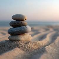 Stacked stones on sandy beach at sunrise create tranquil scene photo