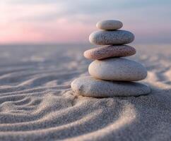 Stacked stones on sandy beach creating a peaceful landscape at sunset photo