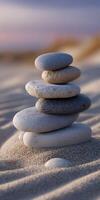Stones delicately balanced on sandy beach at sunset creating a serene atmosphere photo
