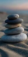 Stacked stones on sandy beach at sunset creating a calming scene photo