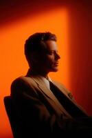 A man is seated in profile, gazing thoughtfully with a calm expression photo
