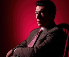 Dramatic portrait of a man in a stylish suit with a red background photo