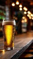 Golden beer in a glass on a rustic wooden bar surrounded by warm lights photo