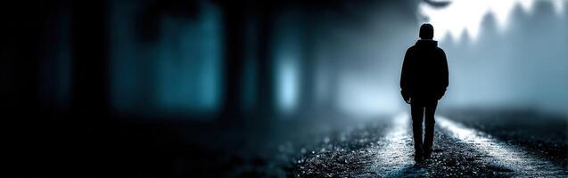 Lonely figure walking on a misty path in a dark forest at twilight photo