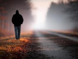 Person walking along a foggy path in the early morning light photo