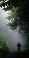 Mysterious figure walking through a foggy forest path in early morning light photo
