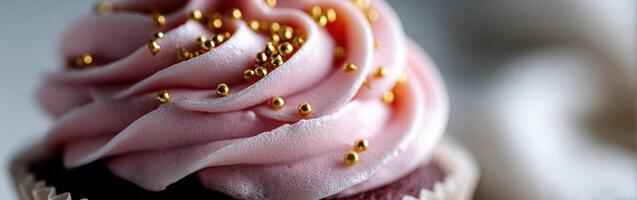 Delicious pink frosted cupcake with golden sprinkles displayed close up photo
