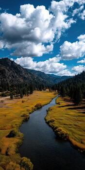 Scenic river flows through golden fields and mountains on a sunny day photo