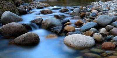 Gentle stream flows around river rocks in early morning light photo