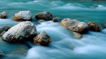 Fast flowing river water rushes past several large rocks photo