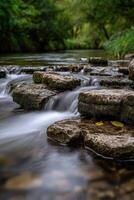 Water flows smoothly over moss covered stones in Peak District photo