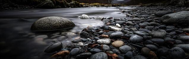 Still river flows over rocky shoreline in late afternoon photo