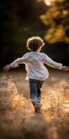 Boy runs through a field with arms outstretched at Sunset photo