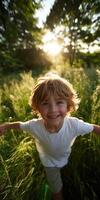 Boy smiling with arms outstretched in grassy field at sunset photo