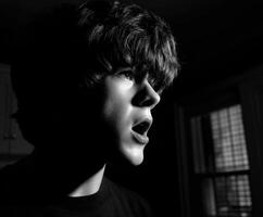 Young man looks shocked with mouth open in dim light photo
