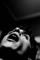 Person looks upwards with mouth open in black and white photo