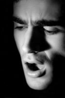 Close up of man singing in a low light setting photo