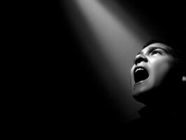Man shouts towards bright light in the darkness photo