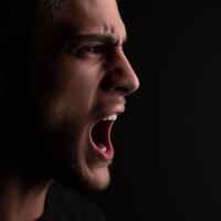 Man shouting in anger in front of black background profile photo