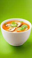 A bowl of mushroom soup with noodles is on a green table, suitable for menu photo