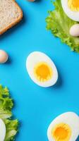 Boiled Egg slice on a blue surface with lettuce and bread for a diet or healthy recipe photo