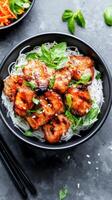 Chicken bites, noodles, and vegetables being served in a dark bowl. Food photography use photo