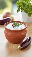 Creamy dip of cooked eggplant and spices served in a rustic bowl on a wooden table in daylight photo
