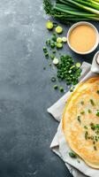 Crepe with scallions and sauce on a gray surface for breakfast menu and food blog use photo