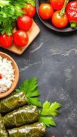 Dolma dish with tomatoes, herbs, and rice bowl on a dark stone background, top view. For menu usage photo