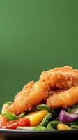 Fried chicken bites sit on a fresh salad with tomatoes and onions, against a green backdrop photo