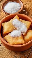 Fried dough in bowl, sugar on top, in a rustic setting. Close up shot, ideal for food blog or recipe photo