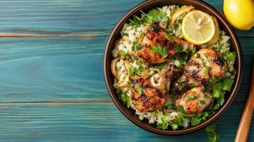 Grilled chicken drumsticks with cauliflower rice, lemon, and herbs on a blue rustic table photo