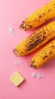Grilled corn cobs with butter and salt on a pink background for recipe book or menu images photo